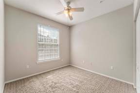 A room with a ceiling fan and a window with blinds.