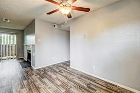 A room with a ceiling fan and wooden flooring.