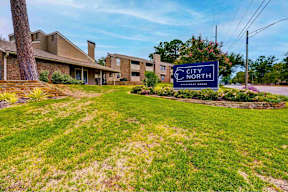 A grassy area in front of a building with a sign that says City North.