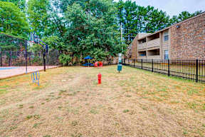 A red fire hydrant sits on a grassy area in front of a brick building.