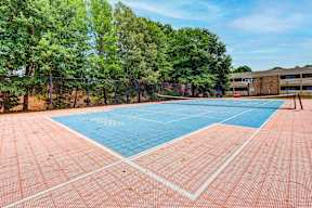 A tennis court surrounded by trees and a building.