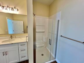 A white bathroom with a sink, mirror, and shower.