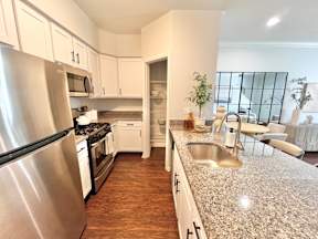 A kitchen with a stainless steel refrigerator and a granite countertop.