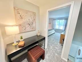 A room with a desk, chair, and a painting on the wall.