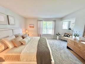 A bedroom with a large bed, a chair, and a dresser.