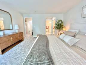 A bedroom with a large bed and a dresser with a mirror.