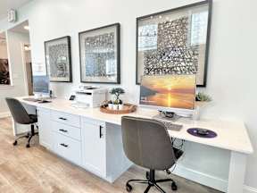 A white desk with a computer and a chair in front of it.