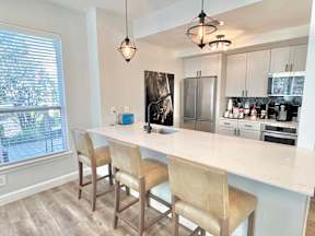 A kitchen with a white countertop and beige chairs.
