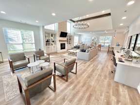 A spacious living room with a fireplace and a kitchen area in the background.