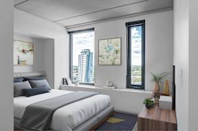 A bedroom with a large bed and a window overlooking a cityscape.