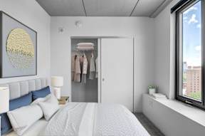 A bedroom with a large bed and a window overlooking a cityscape.