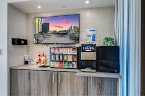 A modern kitchen with a large TV screen showing a sunset scene.