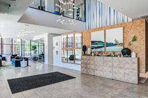 A reception area with a wooden wall and a black mat on the floor.