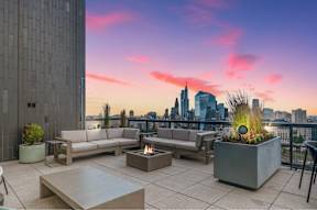 A modern outdoor seating area with a view of the city skyline at sunset.