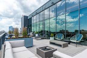 A modern outdoor seating area with white furniture and a fire pit.