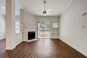 an empty living room with a fireplace and a ceiling fan