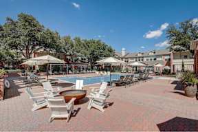 a large pool with chairs and umbrellas and a building in the background