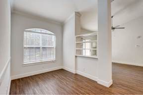 an empty living room with a large window and wooden floors