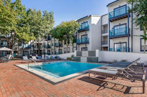an apartment building with a pool and lounge chairs