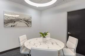 a small meeting room with a round table and white chairs