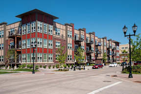 A street view of a city with apartment buildings and cars.