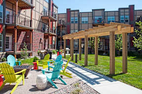 A patio with a wooden pergola and several chairs.
