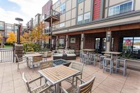 A patio with a table and chairs is surrounded by a fence and trees.