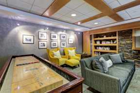 A shiny billiard table is in the middle of a room with a couch and a bookshelf.