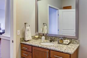 A bathroom with a granite counter top and a large mirror.