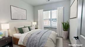 A bedroom with a bed, nightstand, and a plant.