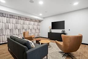 A living room with a grey couch, a brown chair, and a black television.