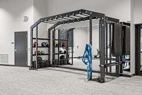 A gym with a squat rack and a blue rope hanging from it.