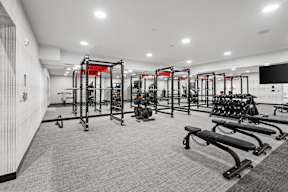 A gym with a variety of equipment including treadmills, weights, and exercise machines.