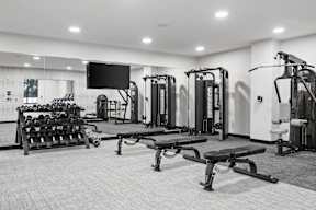 A black and white photo of a gym with a variety of equipment.