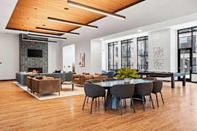 A modern clubroom with a fireplace and a dining table set up.