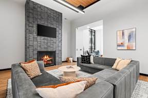 A modern living room with a grey couch, a fireplace, and a painting on the wall.
