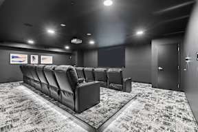 A black and white photo of a movie theater with a row of seats and a carpeted floor.