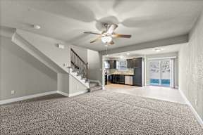 A spacious room with a staircase and a ceiling fan.