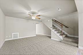 A room with a carpeted floor and a staircase.