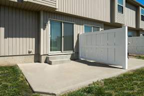 Peculiar, MO, Townhomes - Bradley’s Crossing - Outdoor Patio with Yard, Concrete Flooring, White Fence, and Grass Area.