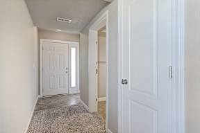 A hallway with a white door and a carpeted floor.