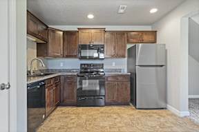 A kitchen with black appliances and wooden cabinets.