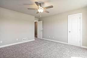 A room with a ceiling fan and carpeted floor.