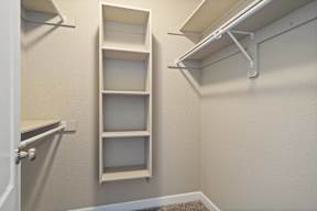 A white closet with a shelf and a door.