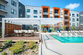 A modern apartment complex with a pool and outdoor seating area.