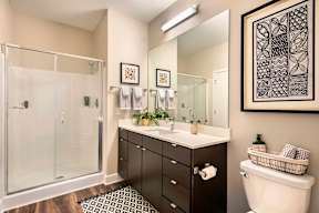 A bathroom with a white toilet, a sink with a mirror, and a shower with a glass door.