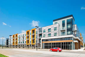 A red car is parked in front of a modern building.