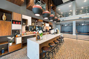 A modern kitchen with a white counter and bar stools.