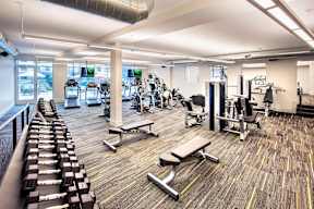 A gym with a variety of equipment including weights and benches.