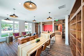 A long wooden table is surrounded by chairs in a room with a red wall.